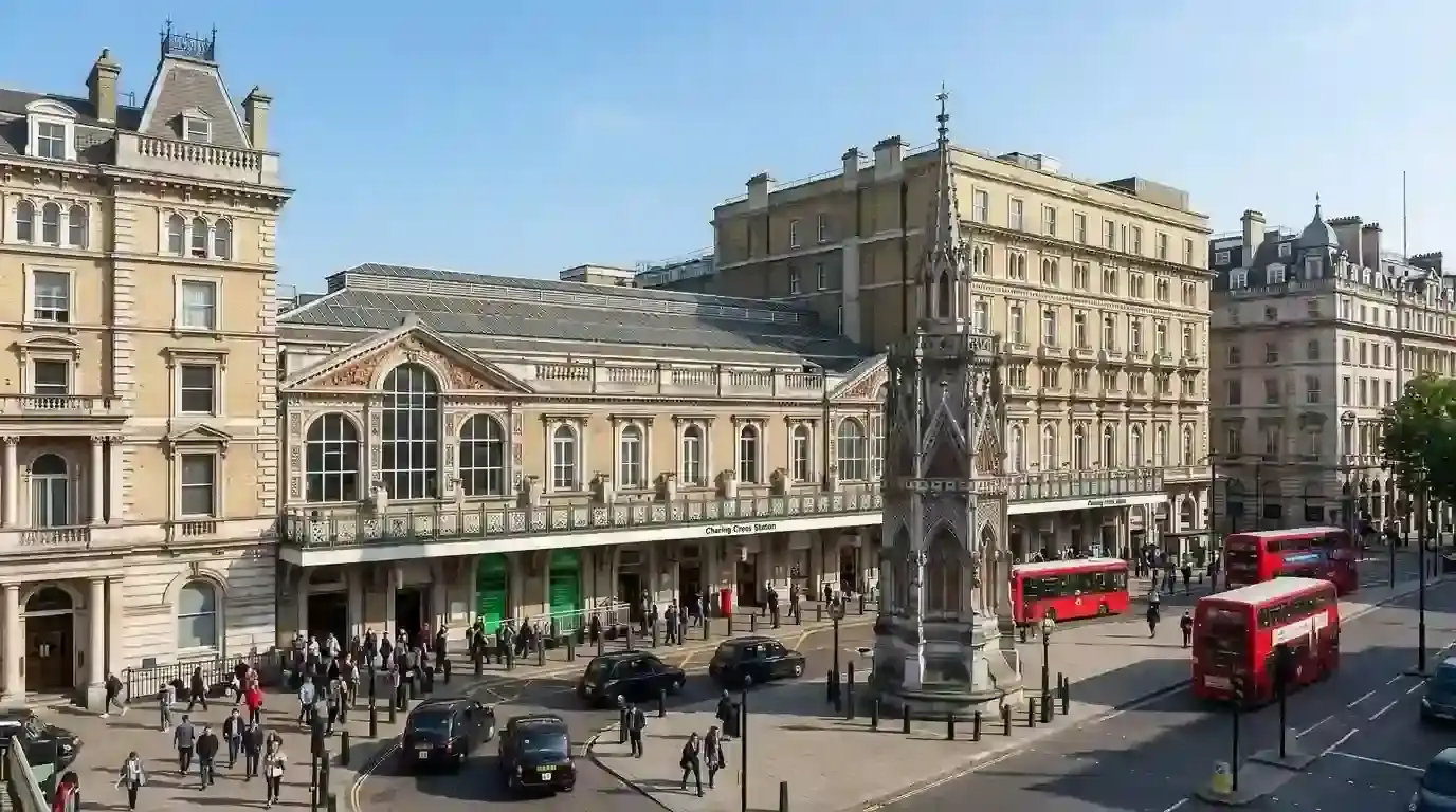 Charing Cross station and the stone cross on the Strand with red buses